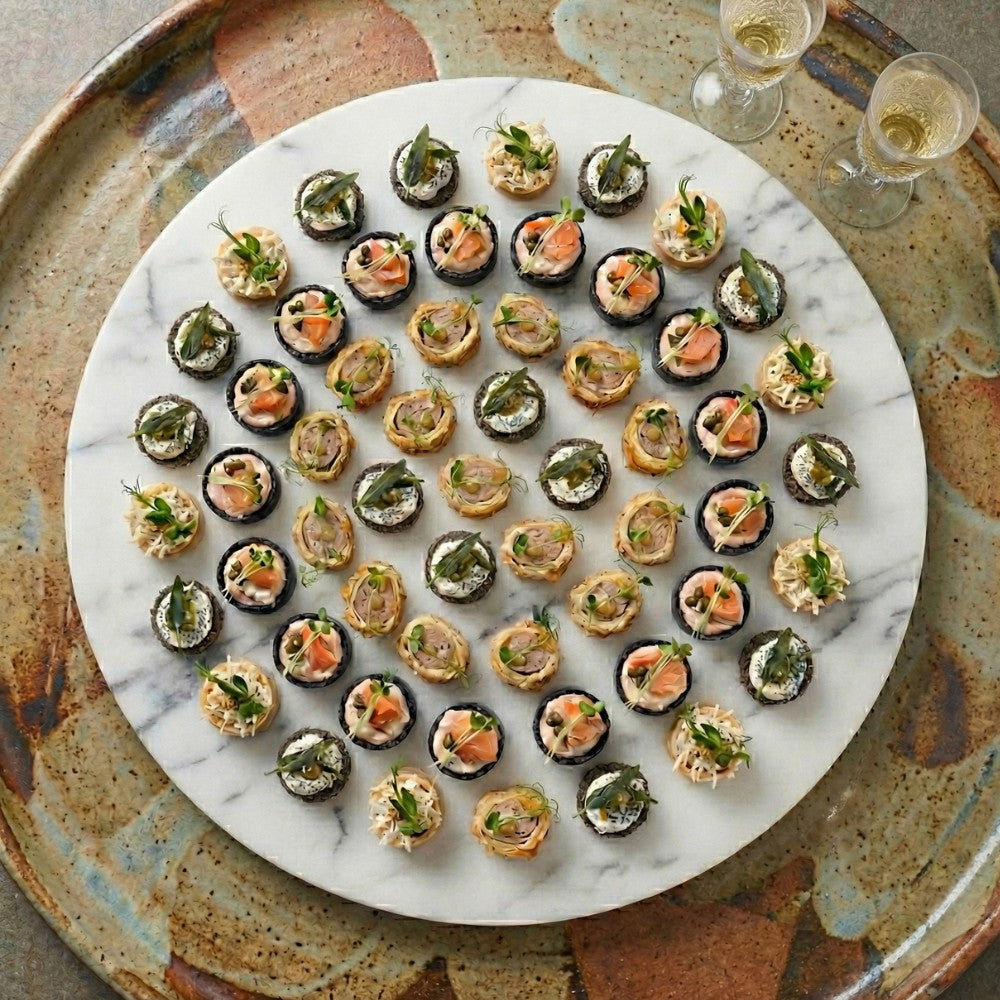 Round marble platter with luxury canapé selection on a rustic surface